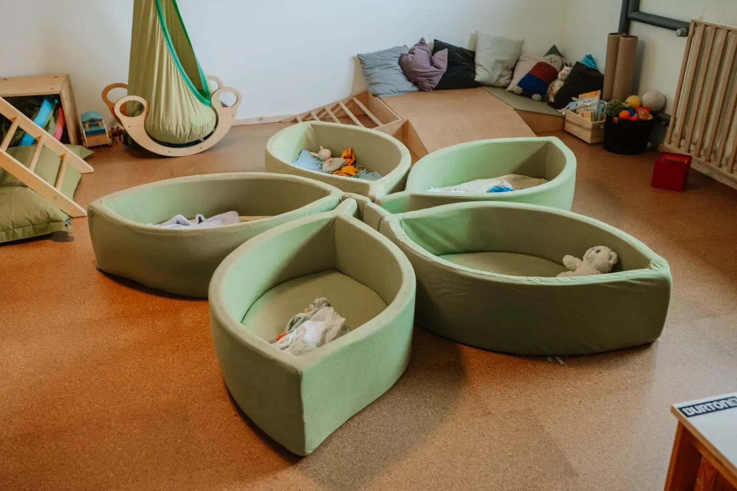 Anna Drobczynsky Kindertagespflege, blattförmige kleine Betten mit Spielzeug darin, zusammen in einer Blumenform angeordnet